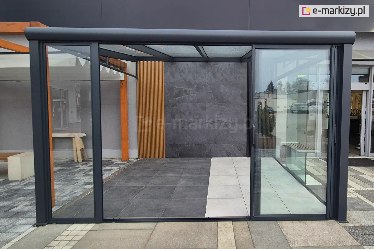 Zewnętrzne drzwi szklane Sotro w stylu loftowym, otwarte i przesunięte na prawą stronę konstrukcji. System przesuwny w eleganckiej, grafitowej ramie aluminiowej eksponuje przestronny taras i zapewnia przejście od frontu.