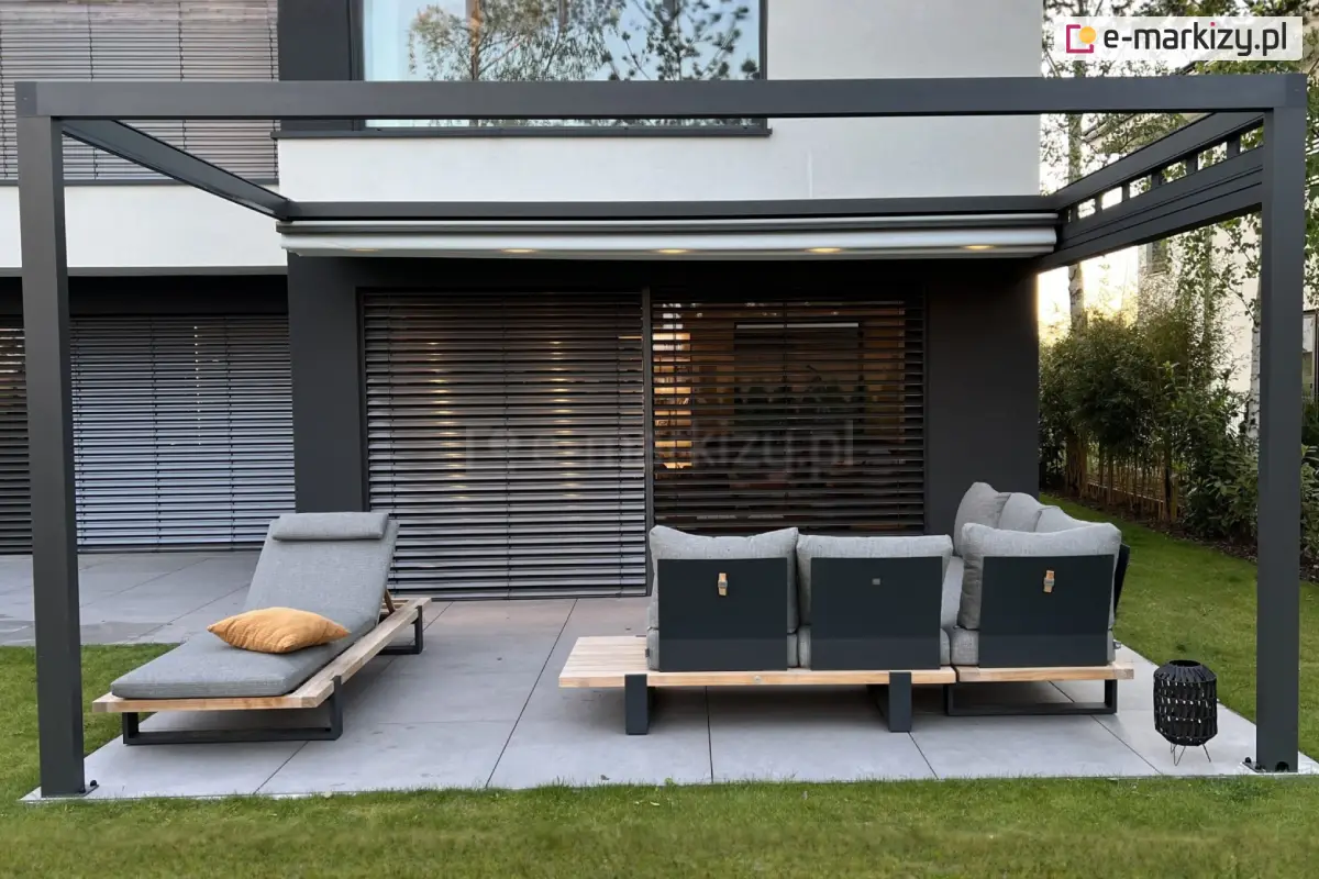 Minimalistyczna pergola tarasowa Square Flat z konstrukcją aluminiową w kolorze antracytowym i zwiniętą tkaniną dachową, zamontowana przy nowoczesnej elewacji budynku z żaluzjami fasadowymi, wyposażona w wygodne leżaki i sofę ogrodową ustawione na jasnym tarasie z płyt gresowych.